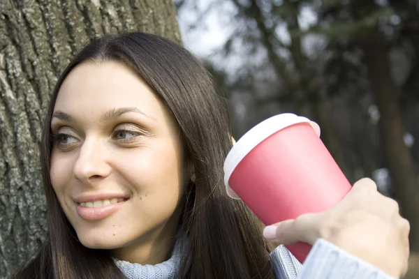 Mooi meisje in een park drinken koffie — Stockfoto