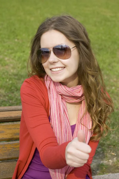 Vacker flicka i en park leende. tummen — Stockfoto