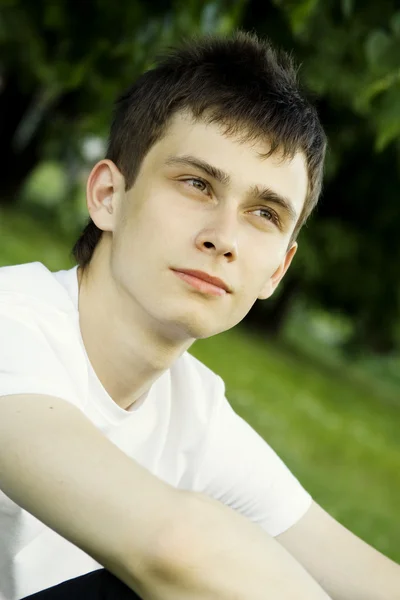 Genç adam parkta oturan — Stok fotoğraf
