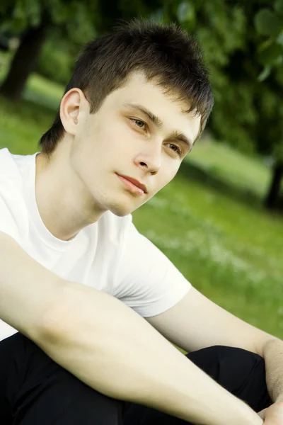 Νεαρός άνδρας κάθεται στο πάρκο — Φωτογραφία Αρχείου