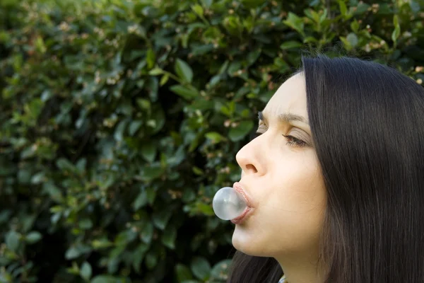 Girl in front of a green leaf blowing bubble — Stock Photo, Image