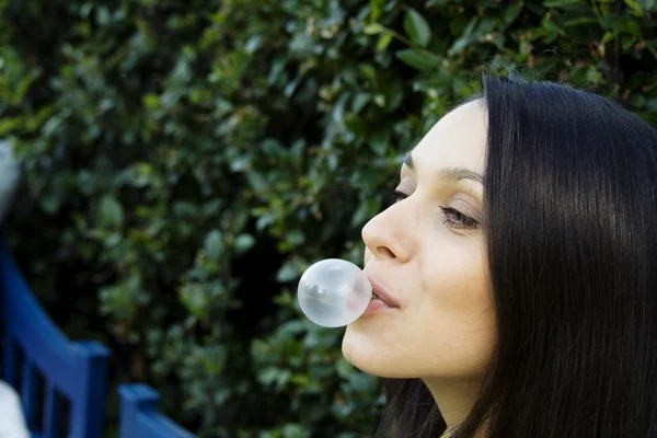 Flicka framför ett grönt löv blåser bubble — Stockfoto