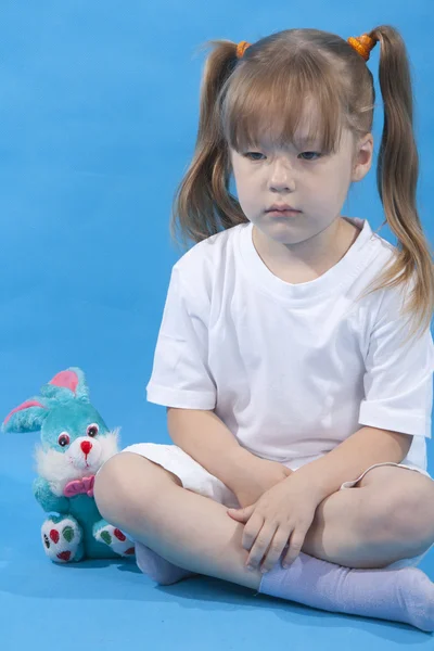 Kleines süßes Mädchen posiert auf blauem Hintergrund — Stockfoto