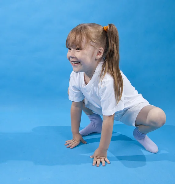 Small girl is posing as frog on blue — Stock Photo, Image