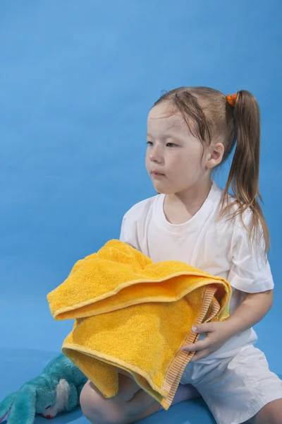 小さな女の子は分離した黄色維持タオルです。 — ストック写真