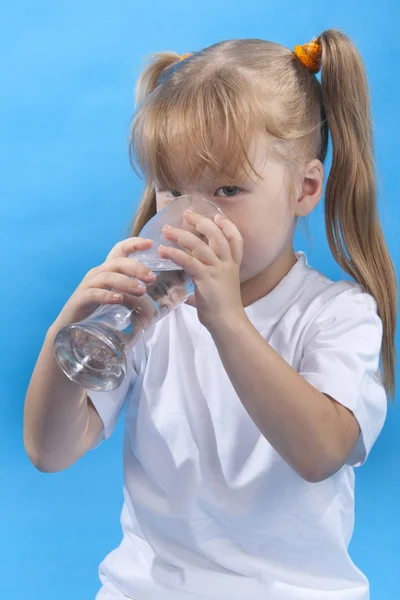 Small cute girl is drinking water on blue background Stock Photo