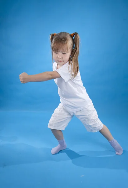 Kleines ernstes Mädchen posiert als Kämpferin isoliert auf blauem Grund — Stockfoto
