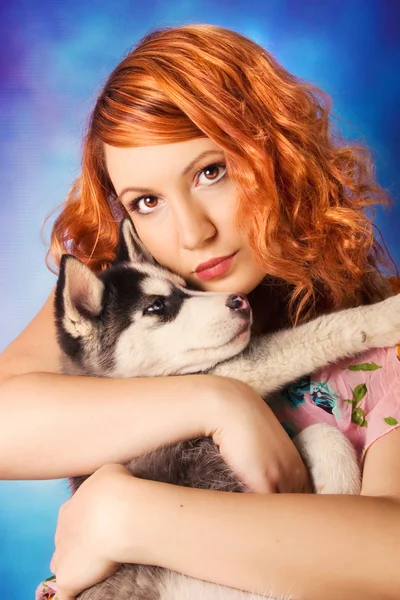 Una rossa che abbraccia un cucciolo husky siberiano — Foto Stock
