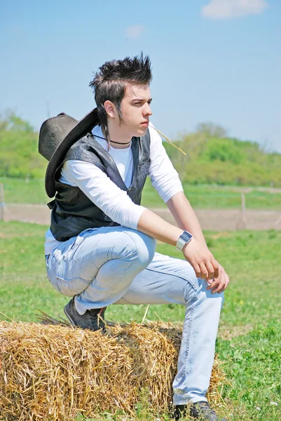 Młody człowiek na beli siana — Zdjęcie stockowe
