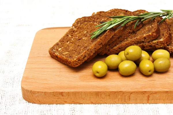 Pão, azeitonas verdes e alecrim e tábua — Fotografia de Stock