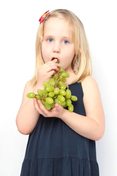 Beautiful girl eats green grapes — Stock Photo, Image
