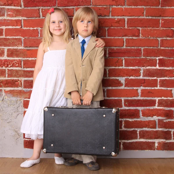 Kleine jongen in een pak en een mooi meisje in een witte jurk — Stockfoto