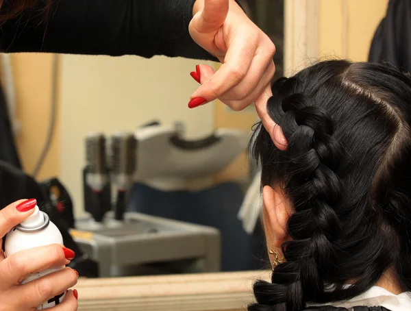 Парикмахер делает прическу на длинные черные волосы женщины — стоковое фото