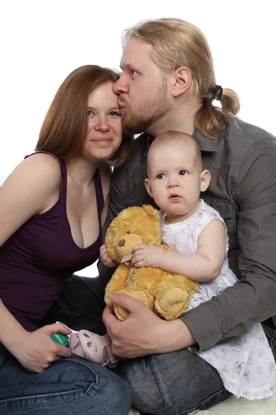 Família feliz: pai segura bebê em seus braços e beija sua mãe — Fotografia de Stock