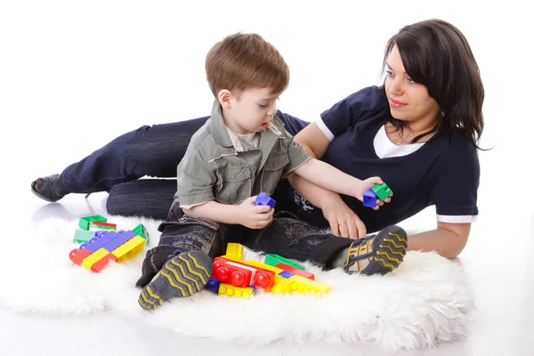 Hingebungsvolle Mutter beim Spielen mit farbigen Blöcken mit ihrem neugierigen Sohn — Stockfoto