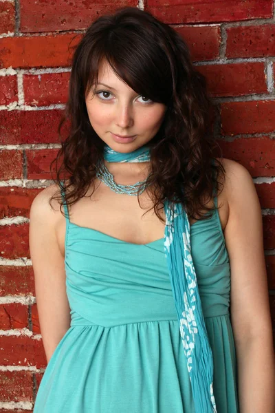 Jovem mulher em um vestido de verão azul contra um fundo de tijolo — Fotografia de Stock