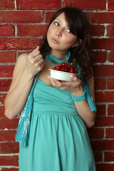 푸른 여름에 아름 다운 갈색 머리 여자 먹는 체리 드레스 — 스톡 사진