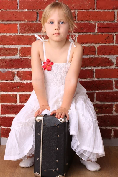 Menina bonita sentada em uma mala. Dança de balé de viagem — Fotografia de Stock