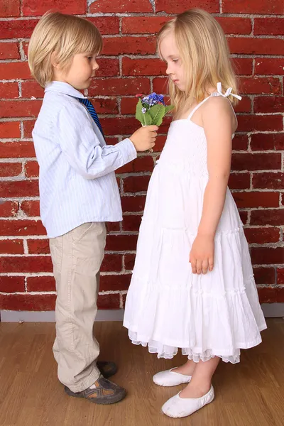 El niño le da a una niña un hermoso ramo de flores. Amor con —  Fotos de Stock