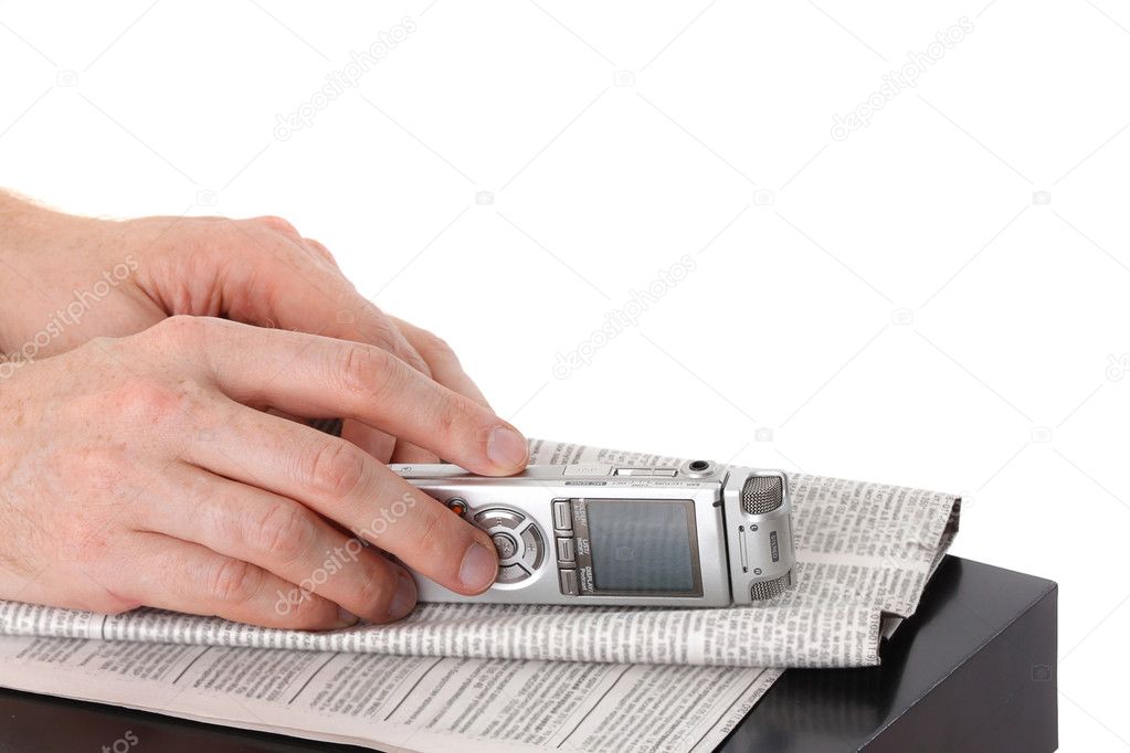 Diktafon in male hand and newspaper on black table isolated on w