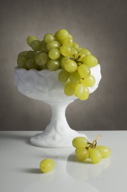 Beyaz bir vazo içinde üzüm küme
