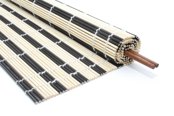 Half-rolled bamboo mat with chopsticks on white — Stock Photo, Image