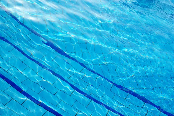 Modré pozadí s slunce odráží ve vodě bazénu — Stock fotografie