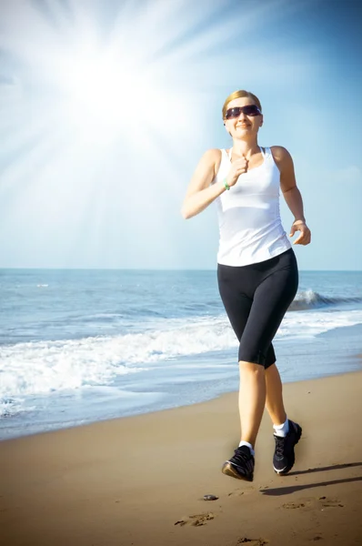 Mladá žena jogging na pláži — Stock fotografie