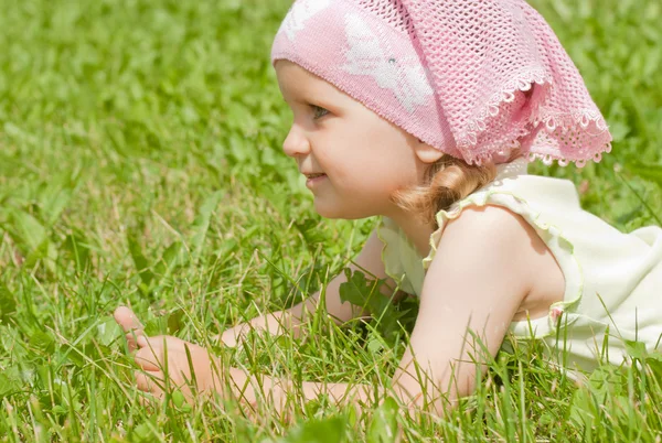 Küçük bir kız bir yeşil çim üzerinde yalan — Stok fotoğraf