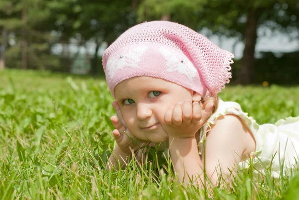 A little girl lying on a green lawn — Stock Photo, Image