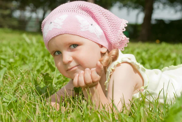 Маленькая девочка лежит на зеленой лужайке — стоковое фото