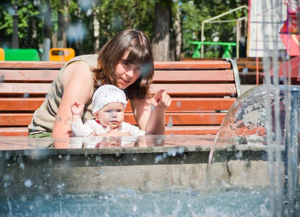 Mom shows her little daughter at the fountain — Stock Photo, Image