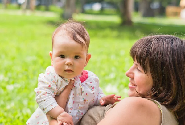 Счастливая мама с маленькой девочкой, играющей на траве в парке — стоковое фото