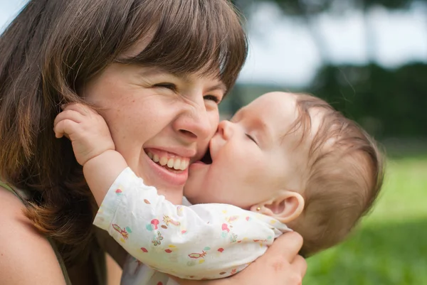 Happy mom with a little girl playing on the grass in the park — Stock Photo, Image