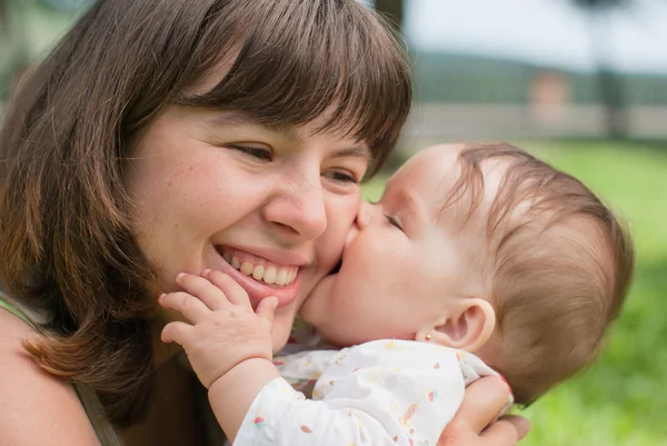 Happy mom with a little girl playing on the grass in the park — Stock Photo, Image
