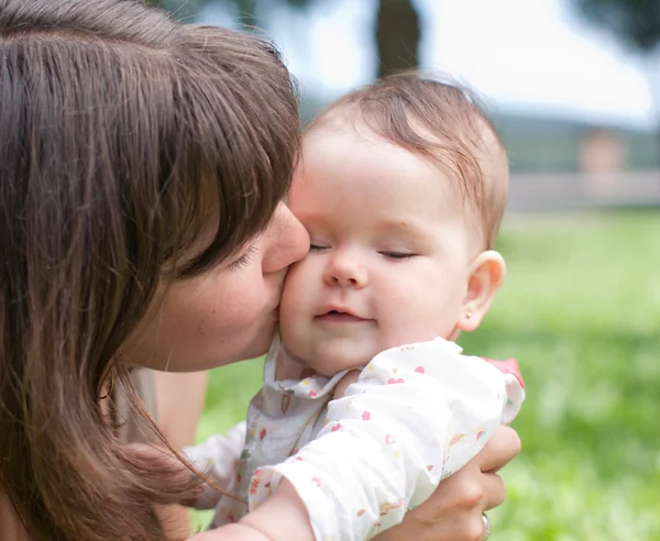 ママ、公園で遊んだ彼女の小さな娘にキスします。 — ストック写真