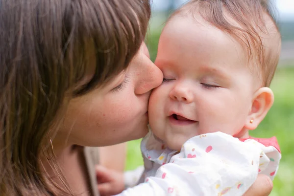 妈妈的吻她的小女儿，在公园里演奏 — 图库照片