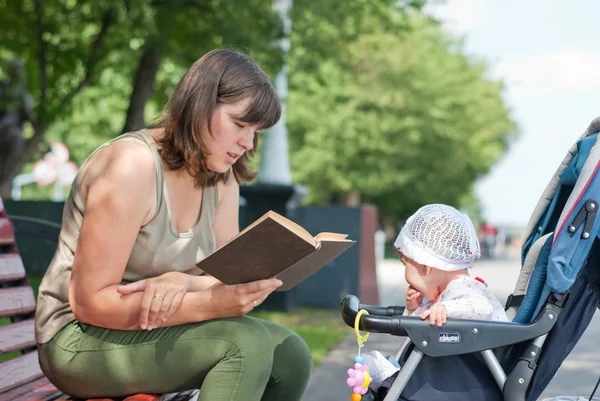 Мама читает книгу о его маленькой дочери в парке — стоковое фото