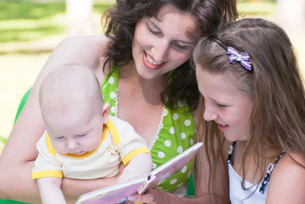 Женщина и двое ее маленьких детей смотрят книгу — стоковое фото