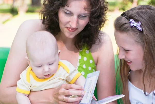 Kobieta i jej dwoje małych dzieci wyglądają książki — Zdjęcie stockowe