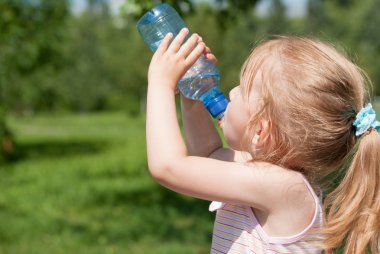 küçük bir kız bir şişeden temiz su içiyor.