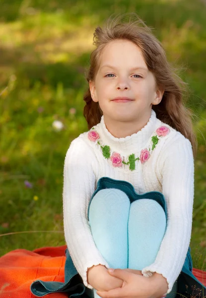 Küçük kız bir Çimenlikte oturan — Stok fotoğraf