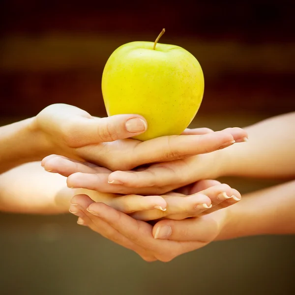 Cuatro manos con manzana — Foto de Stock