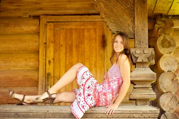 Ragazza si siede sul corrimano capanna log — Foto Stock