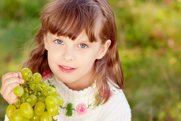 Pequeña hermosa chica come uvas verdes — Foto de Stock