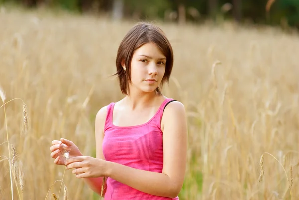 Молодая женщина стоит на поле, держа цветок — стоковое фото
