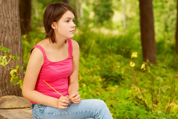 Menina ao ar livre na floresta sentado no log — Fotografia de Stock