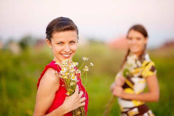 Two young beautiful woman wllith bouquet of camomiles — Stock Photo, Image