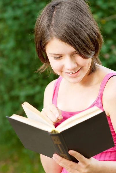 Menina bonita jovem senta-se na ponte e lê livro — Fotografia de Stock