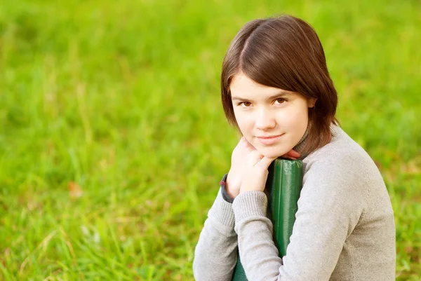 Ung vacker flicka sitter på bron och läser bok — Stockfoto